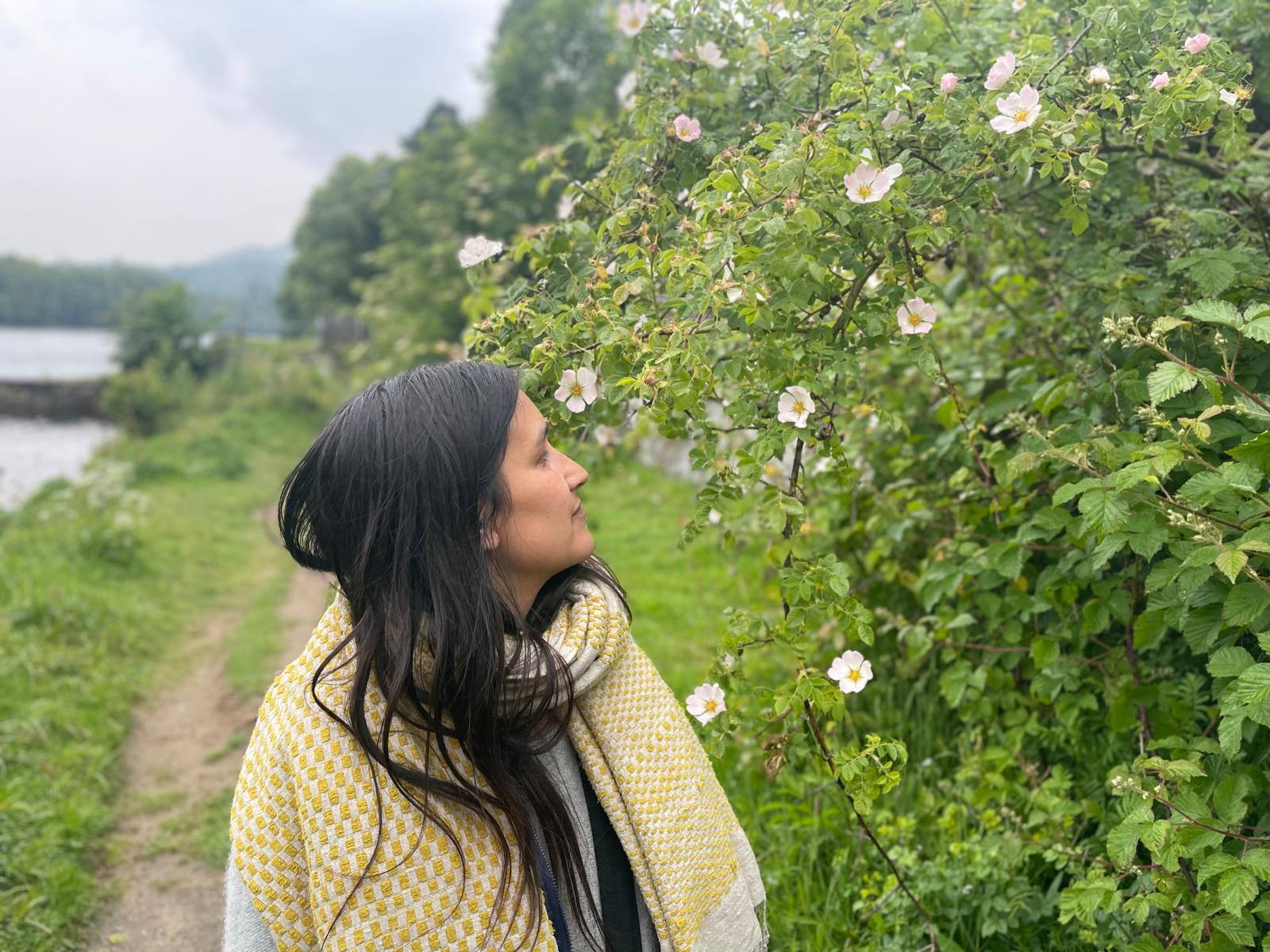 Ros Woman meditating outdoors with herbal rose nearby