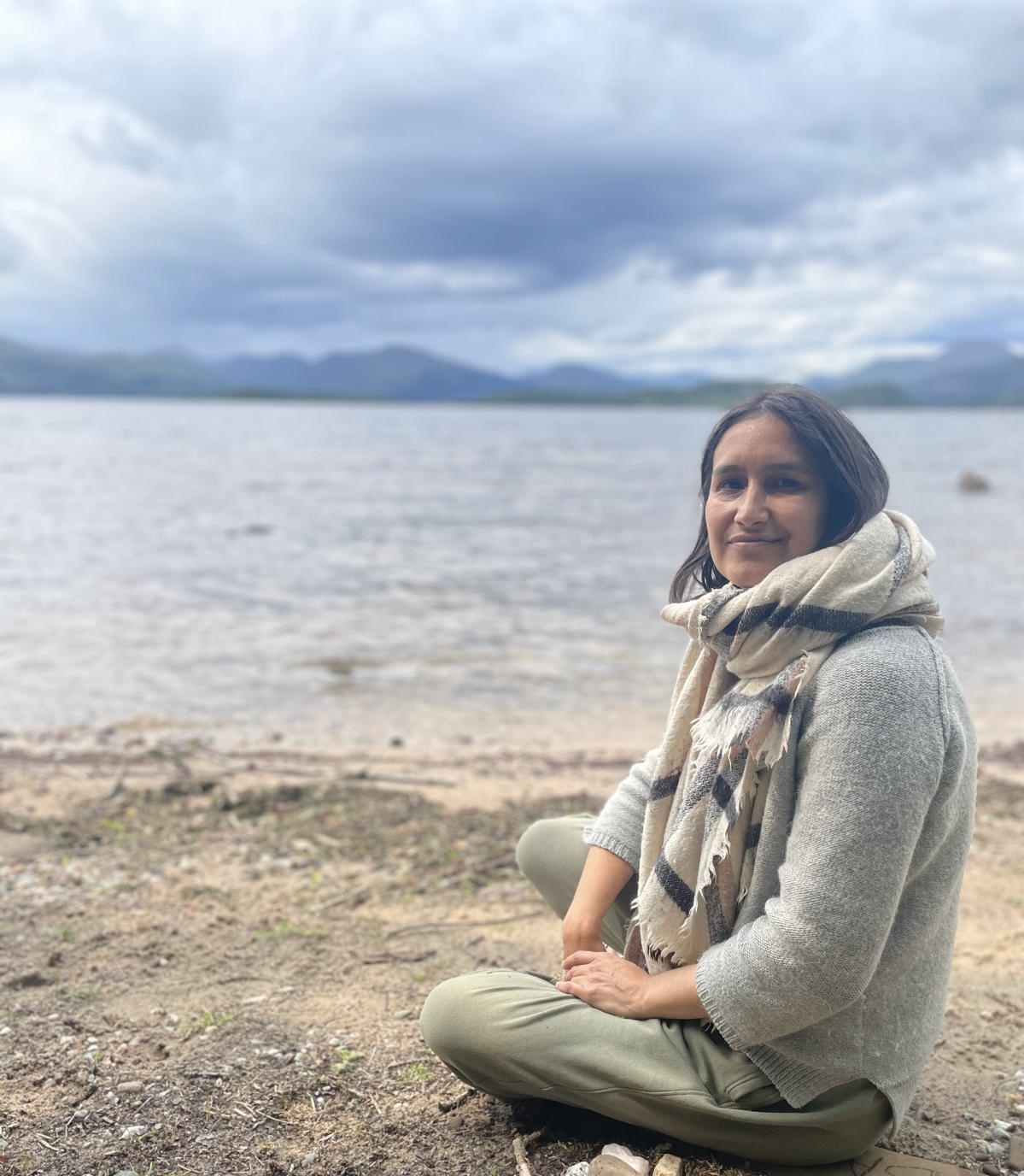 Woman meditating outdoors with herbal rose nearby